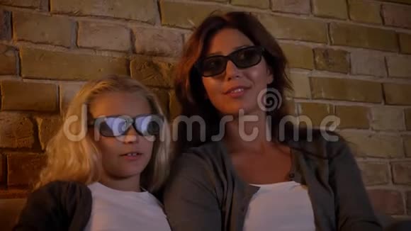 年轻的白种人女性和她的小女儿用3D眼镜看电视的特写镜头变得兴奋和害怕视频的预览图