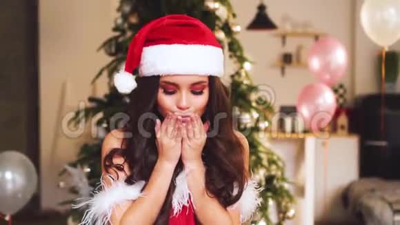 圣诞节里一位迷人的女士戴着一顶深色卷发的新年礼帽慢慢地向你飞吻微笑着视频的预览图
