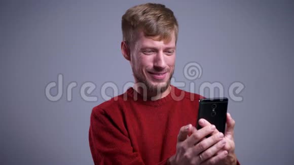 一张迷人的白人男子的特写照片他在电话上打了一个视频电话微笑着挥手致意视频的预览图