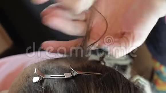 有彩色指甲的女性手在理发师的特写镜头上编织着辫子和辫子视频的预览图