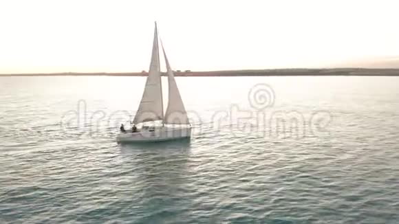 空中观景游艇在日落时在海上航行无人机用帆绕着游艇飞行视频的预览图