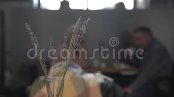 一对夫妇在咖啡馆A喝咖啡在桌子上花瓶里的薰衣草的前景视频的预览图