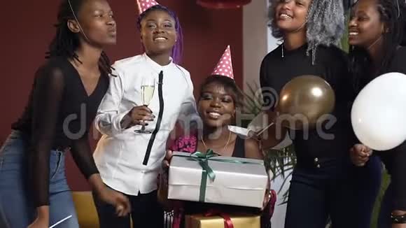 在生日聚会上端着礼品盒的微笑非洲女孩围着她的朋友们视频的预览图