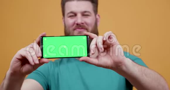 男人骄傲地用绿色屏幕显示他的手机视频的预览图