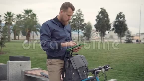 一个骑自行车在户外使用平板电脑的人视频的预览图