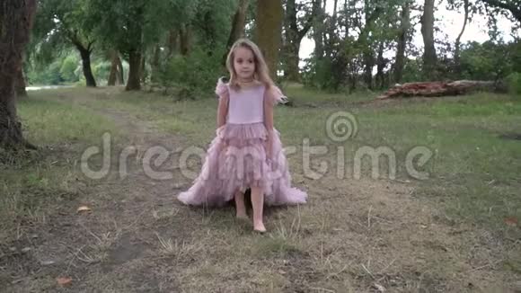 小女孩穿着漂亮的粉红色连衣裙脸上带着微笑在大自然中行走动作缓慢视频的预览图