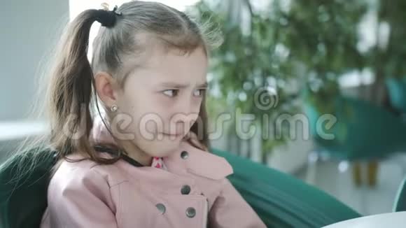 小女孩在窗边的咖啡馆里的一张桌子上哭视频的预览图