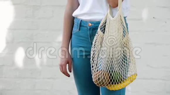 女孩手里拿着可重复使用的网状编织购物袋里面有水果和蔬菜视频的预览图