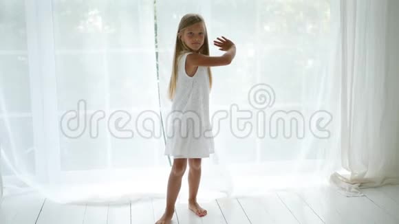穿裙子的女孩正在一扇大窗户的背景上旋转视频的预览图