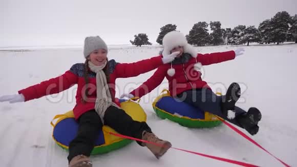 孩子们在冬天骑着充气雪管穿过雪女孩们在冬季公园放松过圣诞节视频的预览图