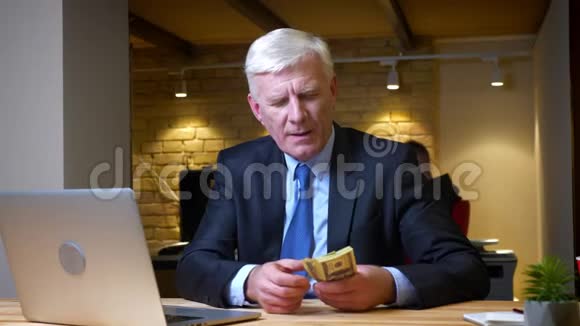 老白种人商人在办公室里坐在笔记本电脑前计算工资的特写镜头视频的预览图