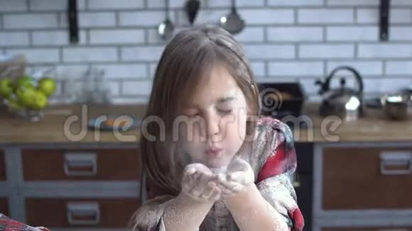 一个小女孩用面粉从她的手掌中吹出面粉满身泥土的肖像可爱的女孩在厨房里玩得很开心视频的预览图