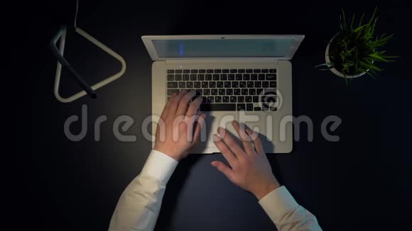 那人晚上坐在桌子旁关掉笔记本电脑摘下眼镜完成工作日的工作视频的预览图