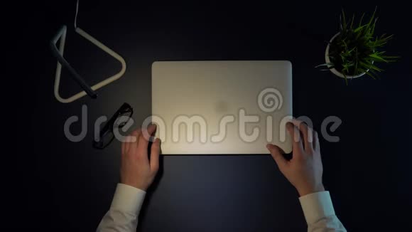一个男商人打开一台笔记本电脑戴上眼镜坐在桌子旁开始工作视频的预览图