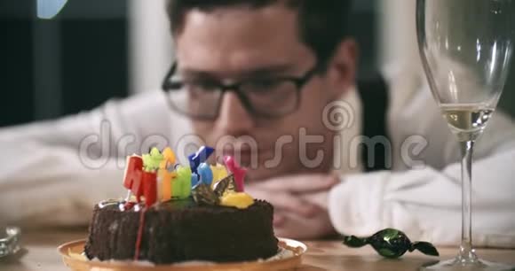 年轻迷人的男人独自坐在桌子旁伤心地吃着烧过的蜡烛上的巧克力失败悲伤的心情社会视频的预览图