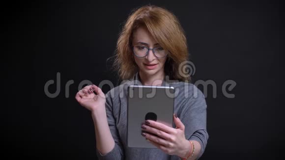 在平板电脑上随随便便地播放视频的有魅力的白种人中年妇女的特写肖像视频的预览图