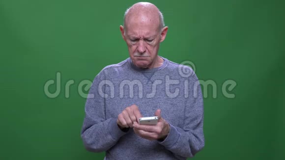 一位老白种人的特写镜头他用手机看镜头背景与绿色隔离视频的预览图