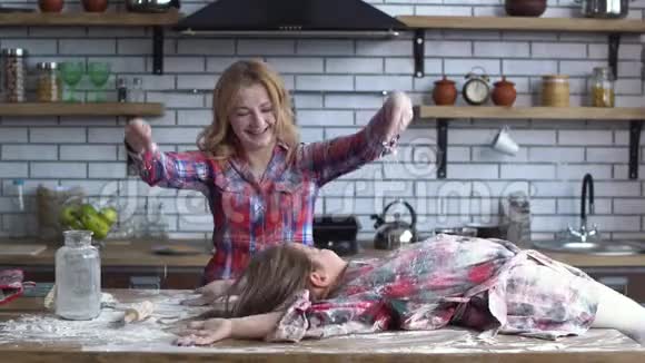 小女孩浑身都是面粉躺在高高的厨房桌子上金发碧眼的漂亮妈妈把女儿洒在地上视频的预览图