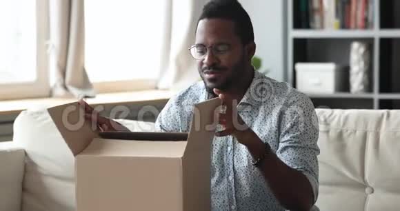 快乐的非洲男人顾客打开纸板箱收到包裹视频的预览图