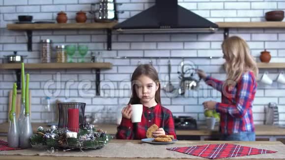 小女儿和漂亮的年轻母亲穿着格子衬衫一起在厨房里吃早餐女孩吃东西视频的预览图