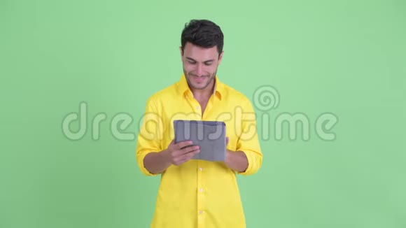 快乐年轻的西班牙裔商人在使用数码平板电脑时思考视频的预览图