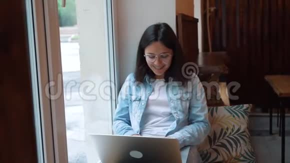 漂亮的女人坐在现代咖啡馆里手提上网本年轻迷人的女性自由职业者视频的预览图