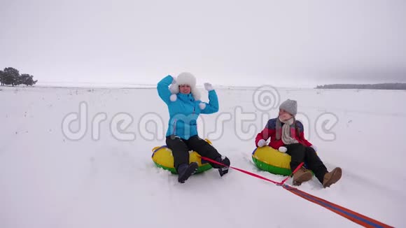 快乐的妈妈孩子们冬天在雪地里溜冰玩雪球妈妈和女儿又笑又高兴家庭游戏视频的预览图
