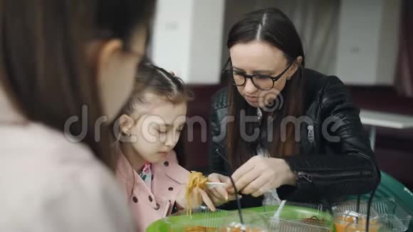 妈妈在咖啡馆里用叉子喂小女儿家庭午餐在咖啡馆视频的预览图