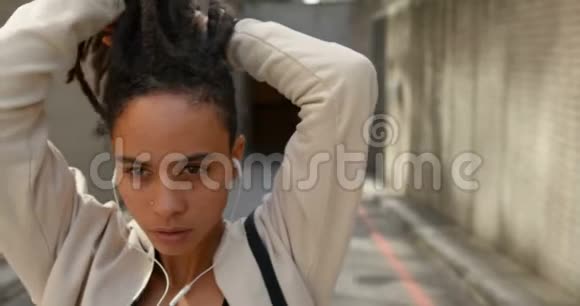 一位年轻的非洲裔美国妇女在城市里绑着她的UPDO的正面景色视频的预览图