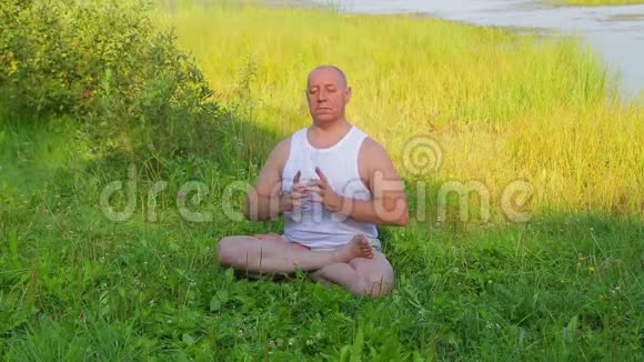 一位中年男子早上在湖上做呼吸瑜伽和冥想视频的预览图