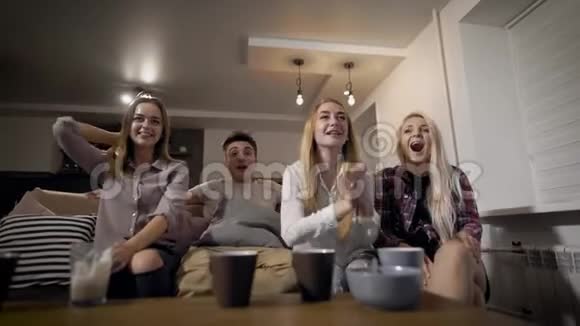 体育迷男孩和女孩坐在客厅的沙发上观看体育比赛欢呼和尖叫视频的预览图
