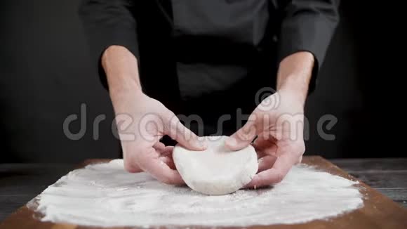 厨师在黑色背景下为披萨准备小麦面团视频的预览图