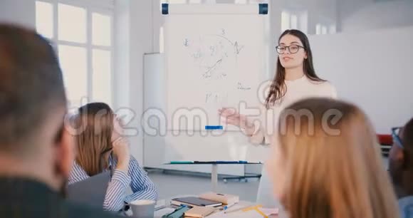 专业的年轻积极的商业专家妇女戴着眼镜在培训研讨会上与快乐的多民族团队交谈视频的预览图