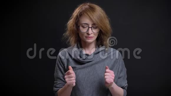 戴眼镜的中年妇女焦虑焦虑的特写镜头在黑色背景下变得紧张视频的预览图