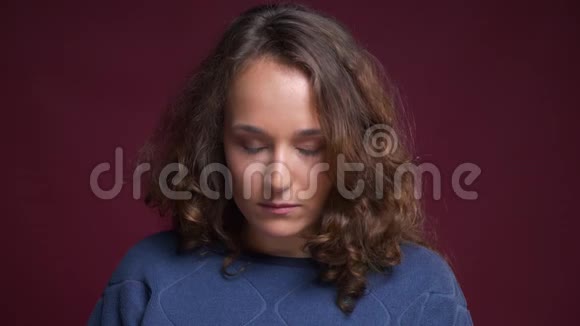 年轻白种人女性的特写肖像卷曲的棕色头发抬起眼睛专注地看着相机视频的预览图