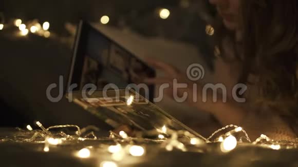 可爱的女人在圣诞节前看家庭相册视频的预览图