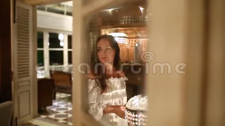 一个美女在等着看着闪闪发光的灯罩镜子反映了发生的事情视频的预览图