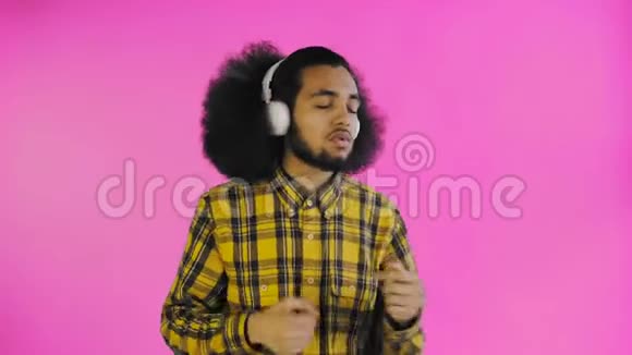 积极的非裔美国人听音乐在他的耳机紫色背景情感概念视频的预览图