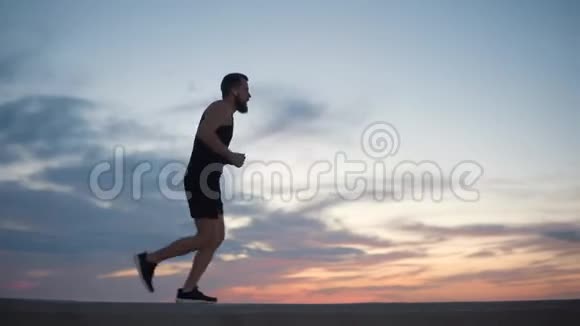 成年男性慢跑者在日落时在阴天跑步视频的预览图