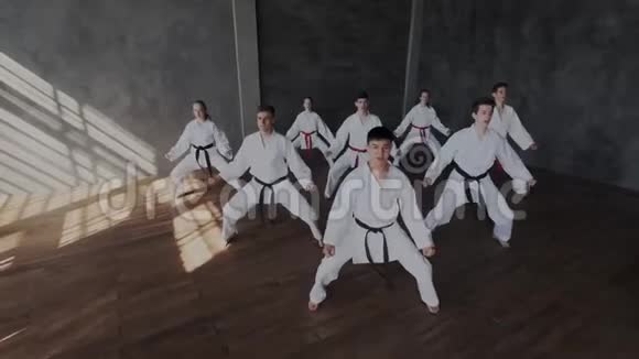 一组身穿白色和服的运动员同步进行一套跆拳道练习我们的战斗学校视频的预览图