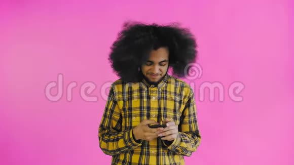 非洲裔美国人的肖像卷发在紫色背景下的智能手机上聊天情感概念视频的预览图