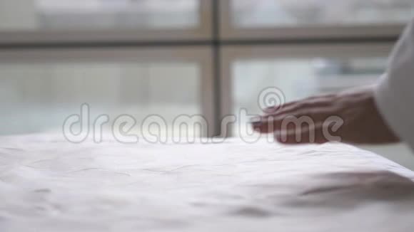 女人手在一张白色的床单上平滑以整理它关门视频的预览图