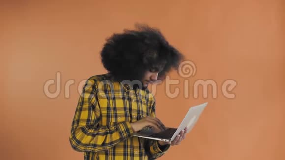 快乐的非裔美国人在橙色背景下使用笔记本电脑情感概念视频的预览图