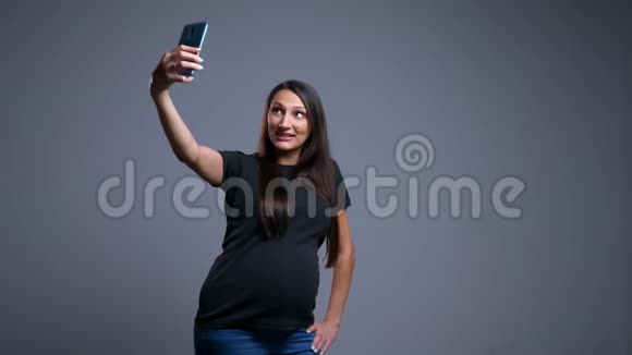 怀孕的白种人年轻女性在电话中自拍并享受乐趣的特写照片视频的预览图