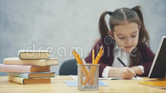 聪明细心的女学生坐在桌子旁做作业在写作过程中铅笔视频的预览图