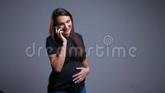 怀孕的白种人年轻女性的特写镜头欢快地在电话中交谈并把她的腹部举在前面视频的预览图