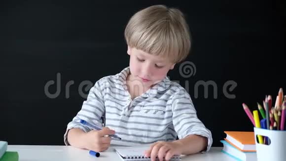 可爱的小男孩在桌子旁画画小学的孩子教育观念回学校去视频的预览图