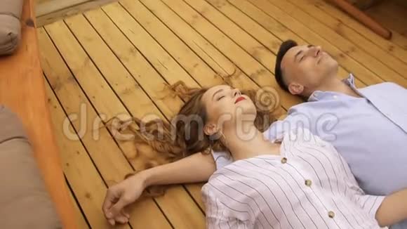 一对年轻夫妇在夏天躺在移动的船甲板上穿着白色深色长发的女孩在温暖的小船上旅行视频的预览图