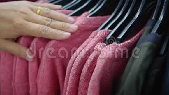 女人的手穿过一排衣服选择这件毛衣视频的预览图