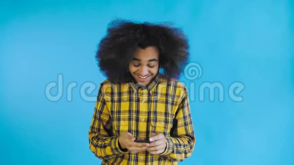 年轻快乐的非洲商人使用电话和获得好消息的蓝色背景情感概念视频的预览图